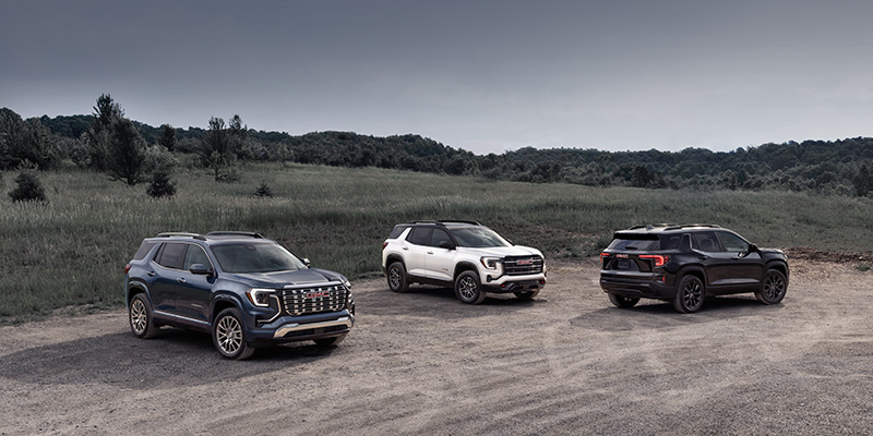 Three 2026 GMC Terrain SUVs parked on gravel in outdoor landscape