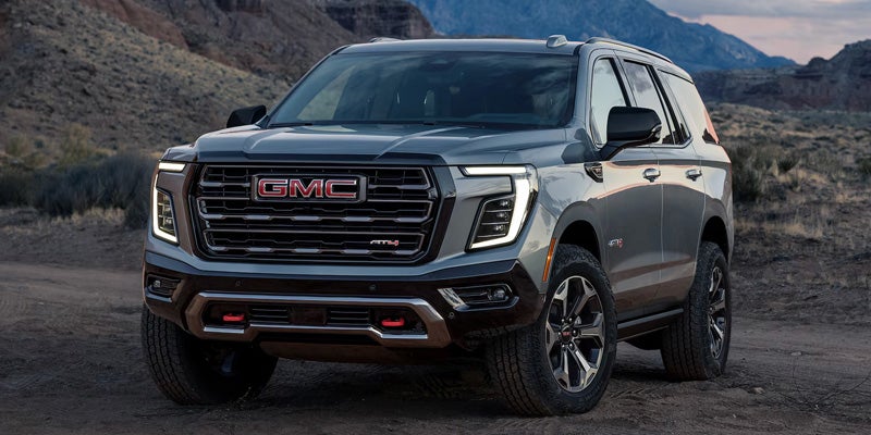 Gray GMC Yukon AT4 SUV parked in a mountain landscape.
